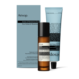 A pump bottle of Solais Replenishing Hand Serum and a tube of Reverence Aromatique Hand Balm together in a carboard box