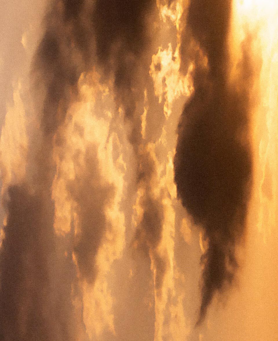 Glowing cloud forms in warm orange light, resembling smoke and firelit sky.