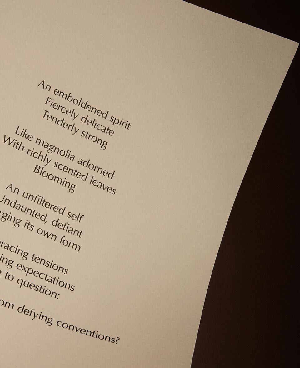 Poem text on a softly lit cream page against a dark background.