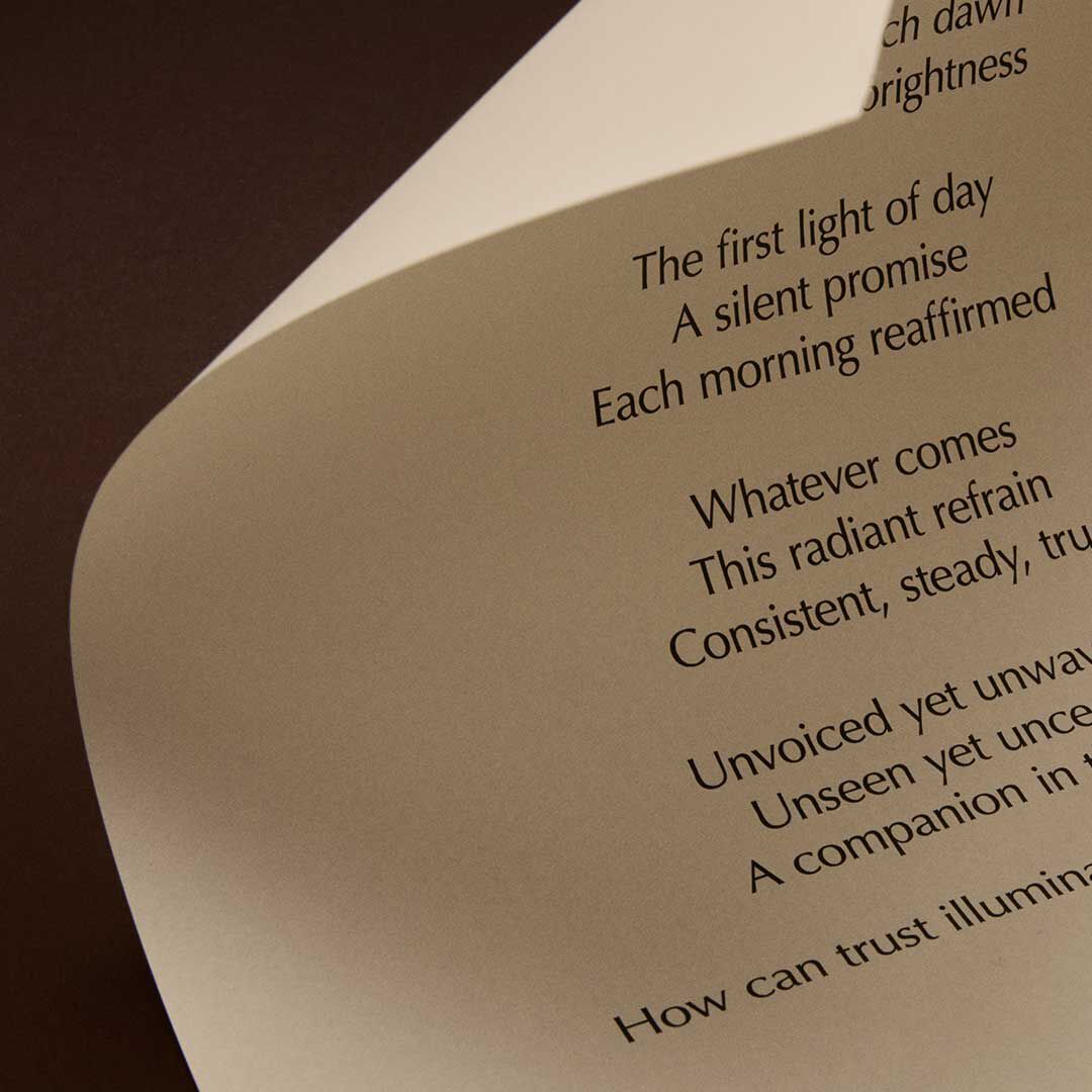 Curved cream page with printed verse lit against a dark brown background.