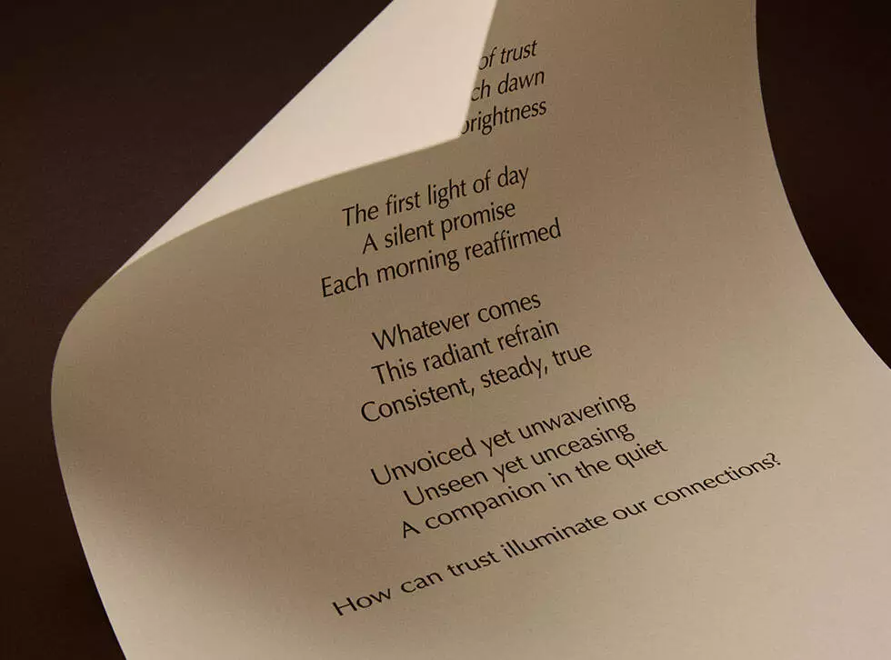 Curved cream page with printed verse against a dark brown background.