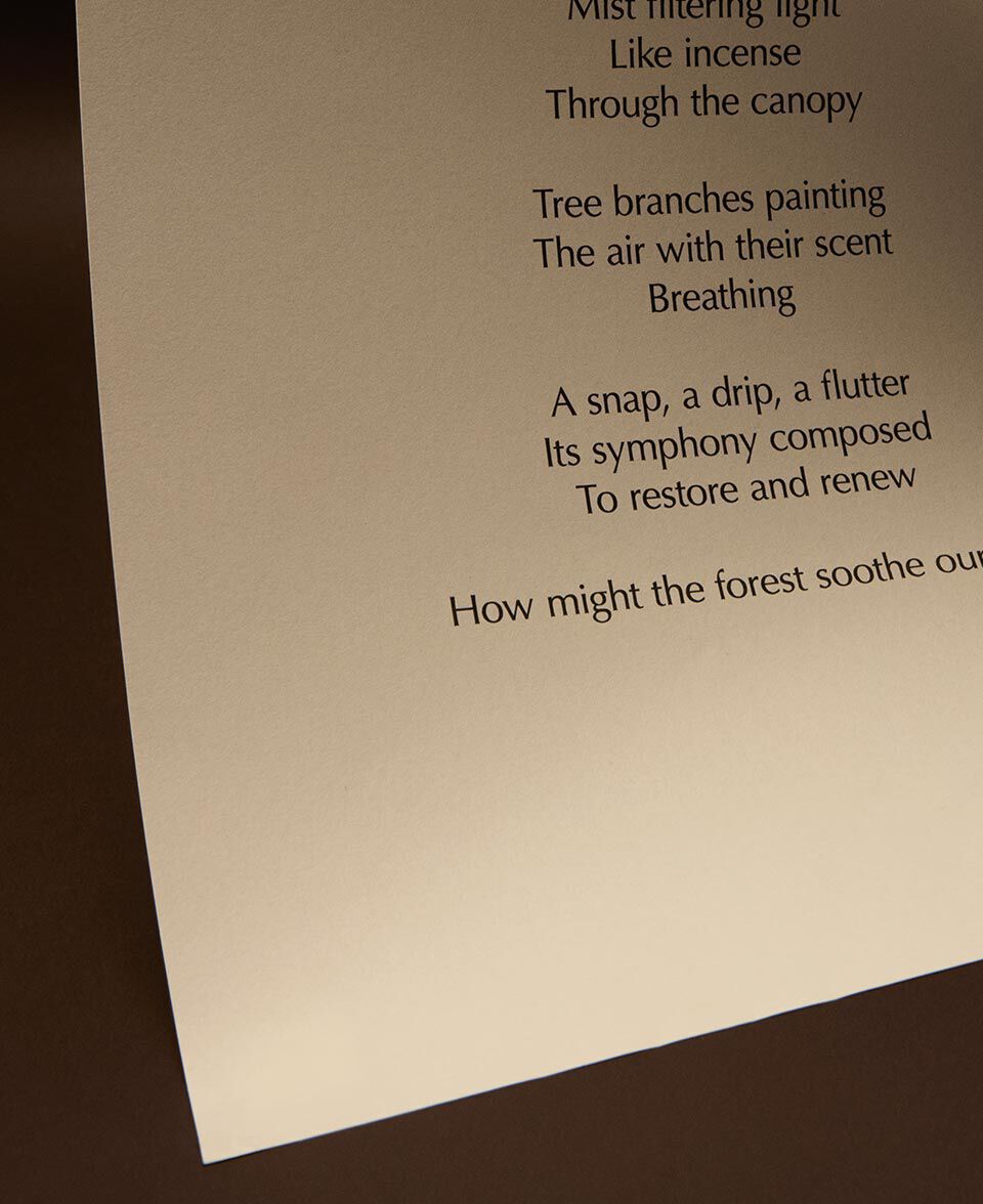 Cream paper sheet with poem text, lit softly against dark brown tones.