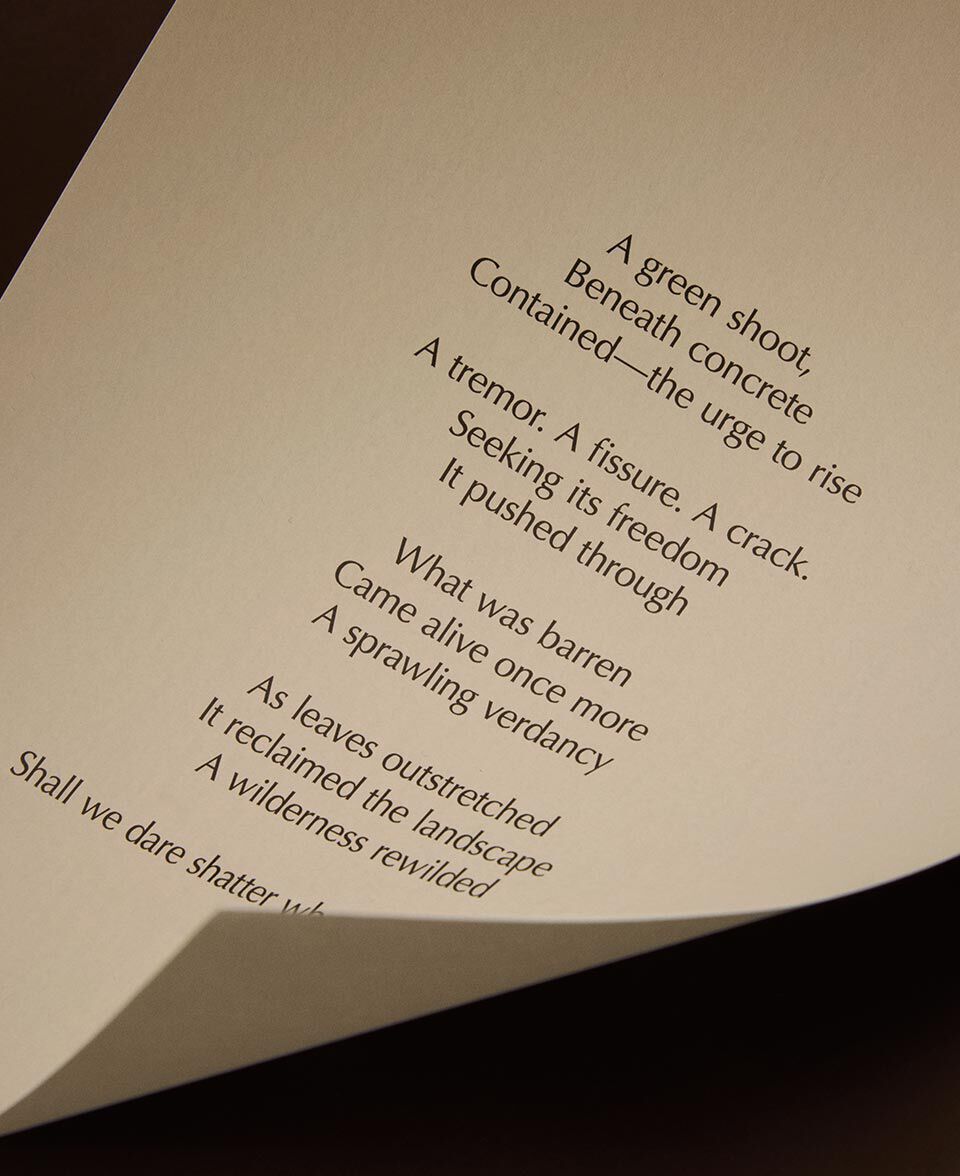 Close-up of a cream paper page with poem lines and a gently curled edge.