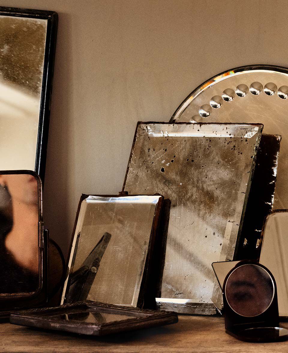 Arrangement of antique mirrors and reflective objects on a wooden tabletop.